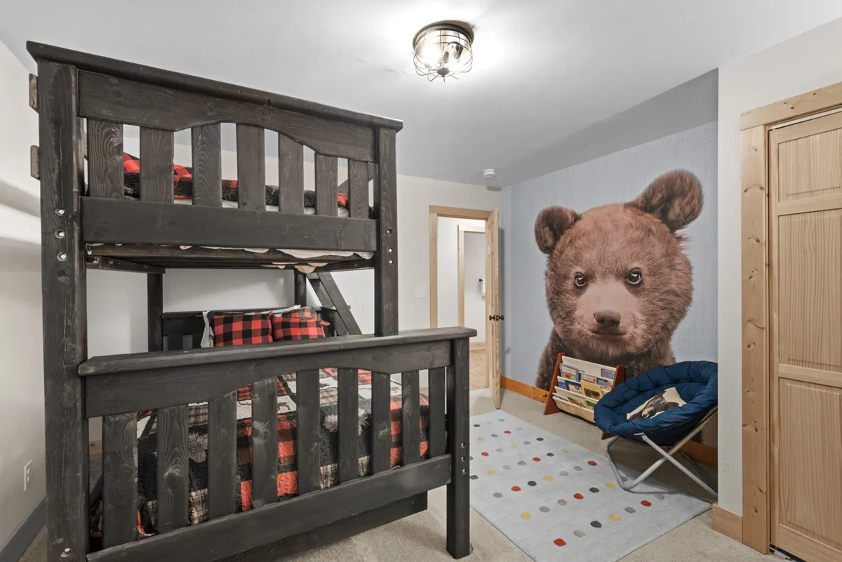 A playful children's nook with a bunk bed, a cheerful bear mural, and a colorful area rug. The space is designed for imaginative play, reading, and cozy sleepovers, making it ideal for young guests.
