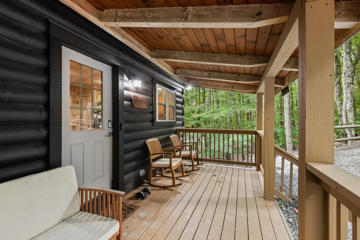 A peaceful wooden deck with classic rocking chairs, set just outside the cabin entrance and framed by vibrant greenery. The space is ideal for quiet moments, morning coffee, or unwinding at sunset while immersed in nature.