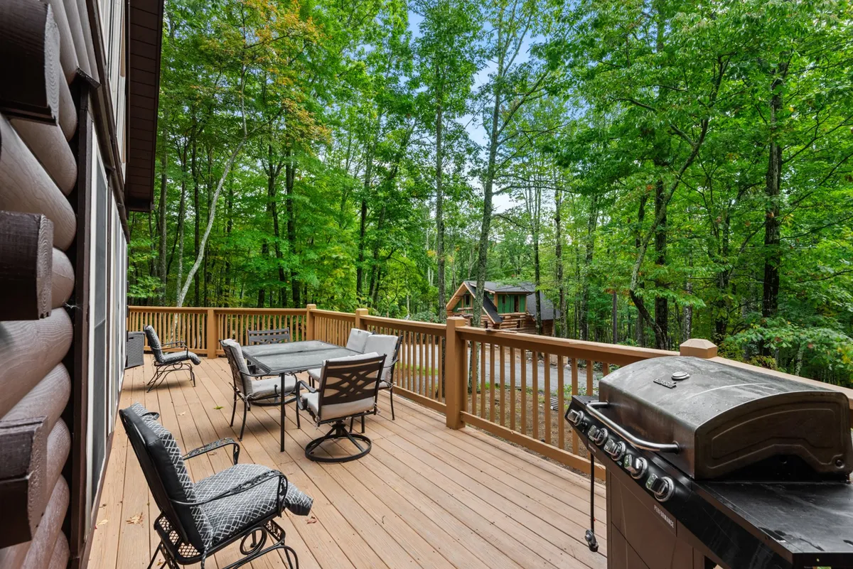This image showcases a spacious outdoor deck with a grill, comfortable seating, and the lush surrounding trees. The arrangement is ideal for social gatherings, barbecues, and enjoying the mountain air, echoing the activity-rich, communal experiences outlined in the text.
